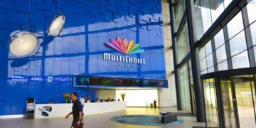 Multichoice and DSTV logo displayed in a modern office interior with people in the background.